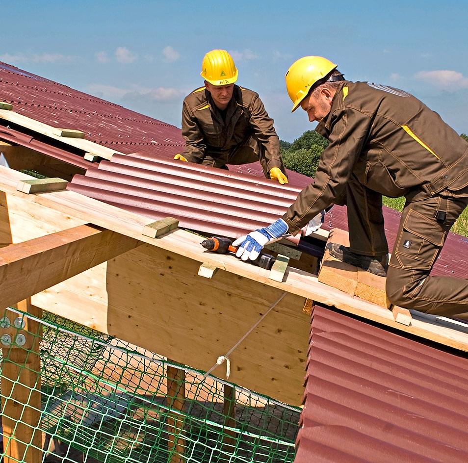 Vorbildliche Arbeitsweise: Es werden Laufbohlen verwendet, und unter der Dachhaut sowie an den Absturzkanten sind Auffangnetze gespannt. Bohlen und Netze sind ebenso bei Reparaturarbeiten auf alten Dächern zu verwenden. Foto: SVLFG