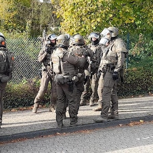 Spezialeinsatzkräfte stehen auf dem Bordstein vor einer Siegburger Schule.